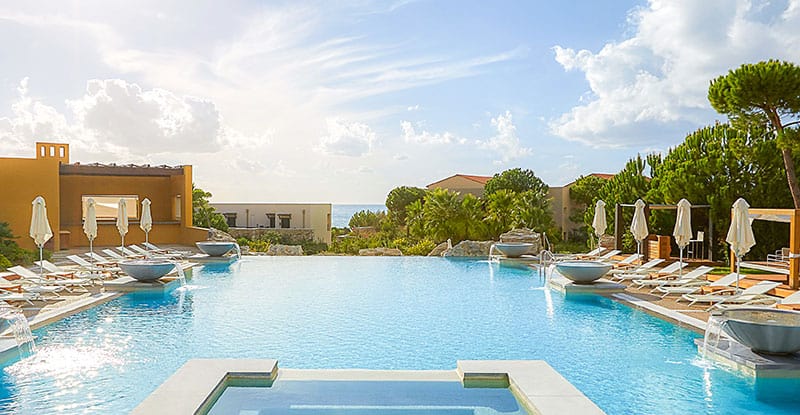Luxury resort pool with loungers and umbrellas—relaxation by the court.
