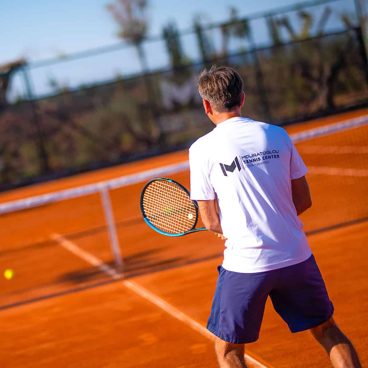 Alex Karvelis, Head Tennis Coach at Mouratoglou Tennis Centre, Costa Navarino, coaching on red clay court