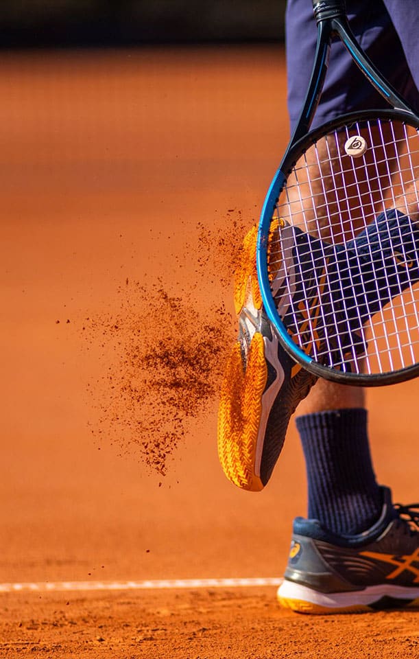 A tennis player's foot is on the ground with a tennis racket